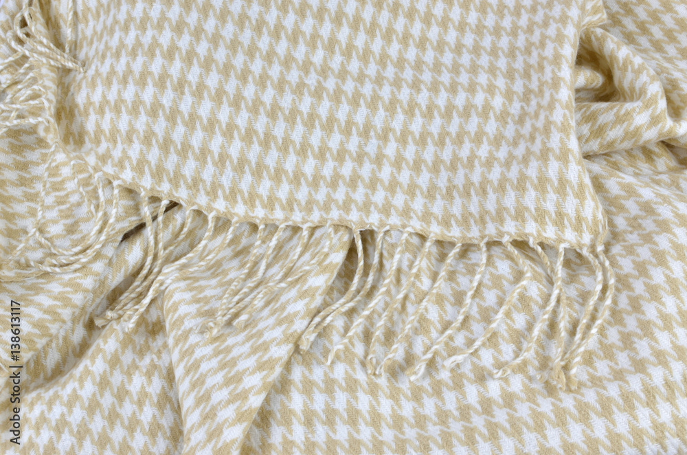 Blanket of soft woolen fabric with beige and white hounds-tooth pattern and with heather