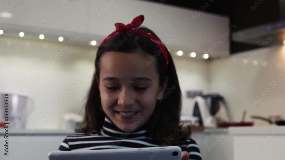 Niña jugando con tablet mientras su madre cocina