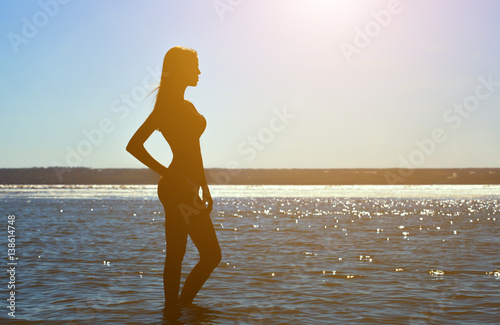 Silhouette of a beautiful, slim girl on a background of a sunset on the beach. photo