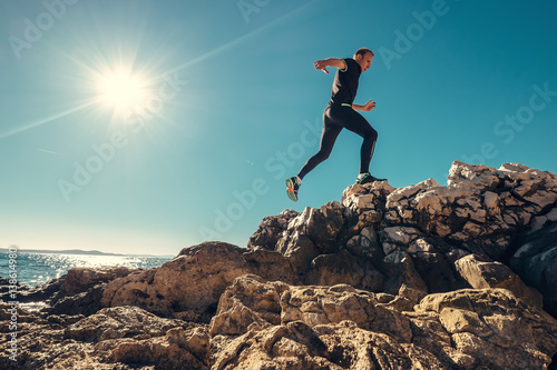 Man runs on rocky sea side