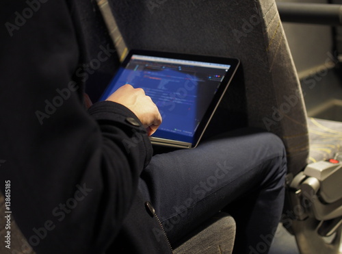 Mann sitzt im Bus und tippt Daten in Laptop ein