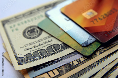 Stack of credit cards and dollars, close-up view.