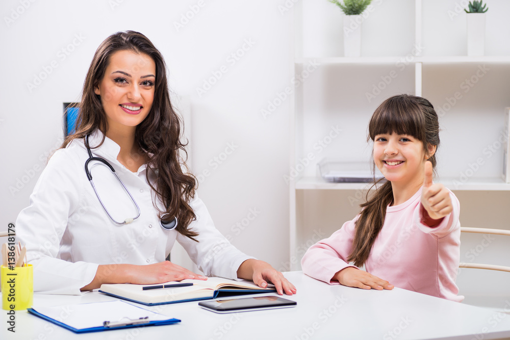 Female doctor and child sitting at the medical office and little girl showing thumb up. Female doctor and child sitting at the medical office and little girl showing thumb up.