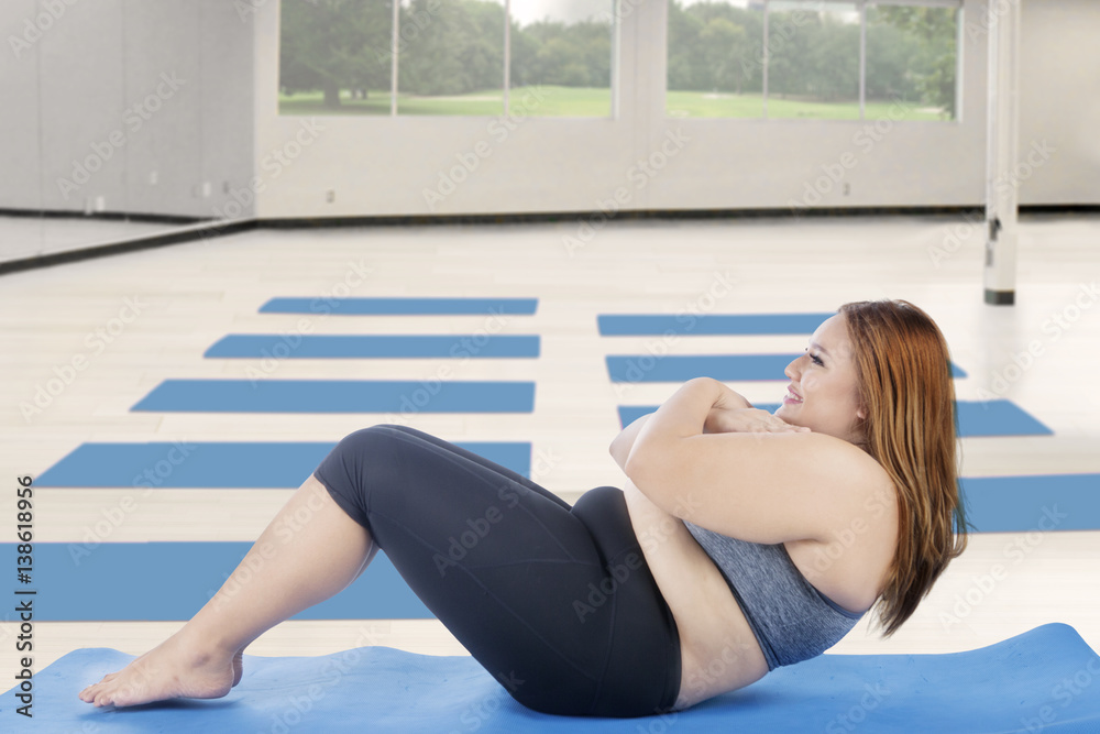 Naklejka premium Overweight girl doing sit-up at gym