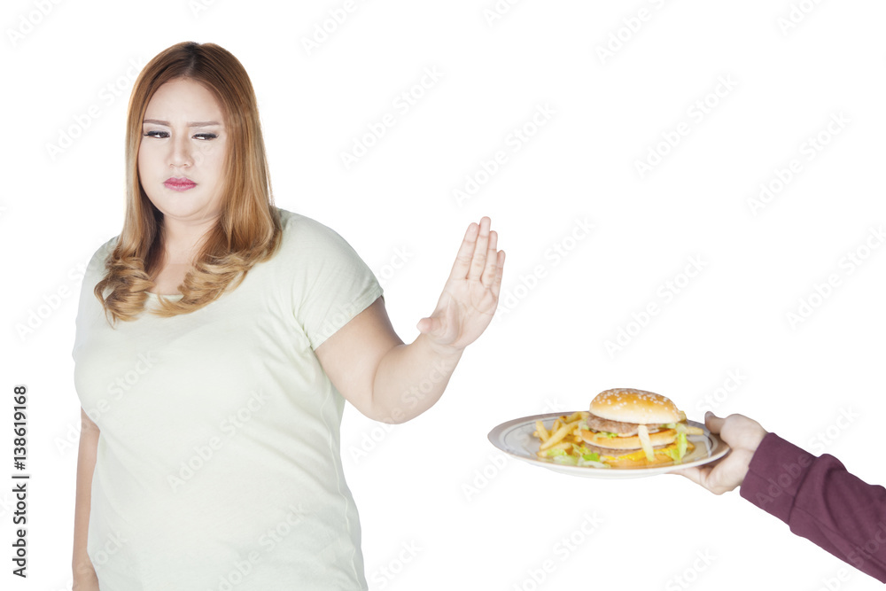 Overweight woman refusing burger on studio Overweight woman refusing burger on studio