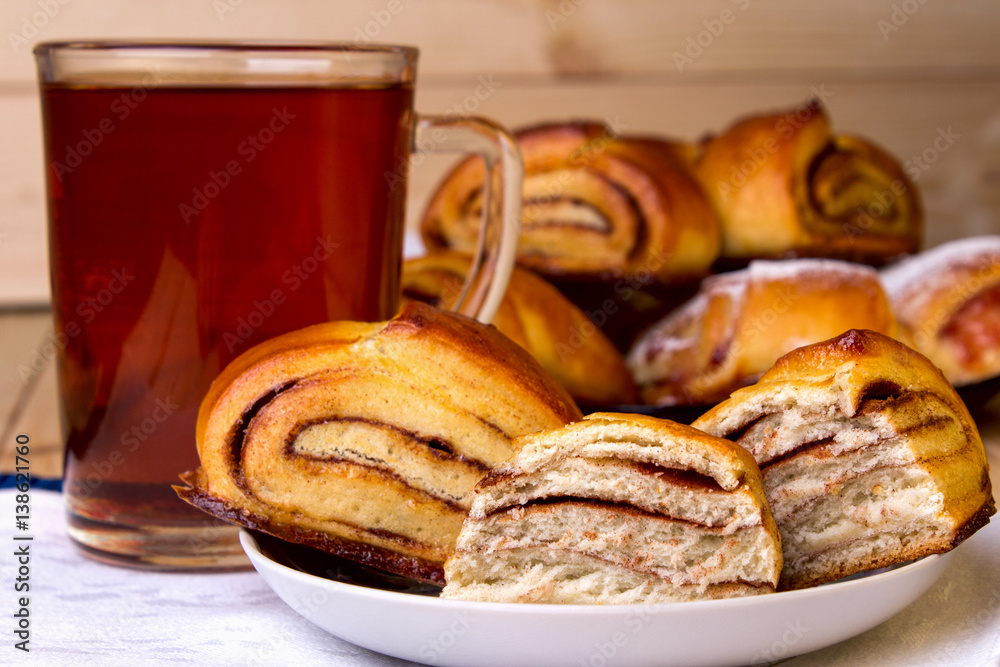 Bun with Cinnamon and a Cup of Black Tea on a Wooden Background.
