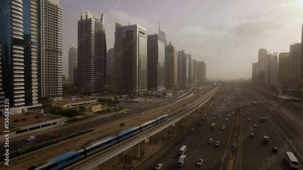 the train goes over the viaduct, along the highway among the skyscrapers in Dubai, UAE the train goes over the viaduct, along the highway among the skyscrapers in Dubai, UAE