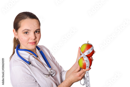 Dietary food that instructs you to a physician nutritionist. Slim dietician holding dietetically apple red color with a measuring tape. The doctor in a white coat and a stethoscope around his neck photo