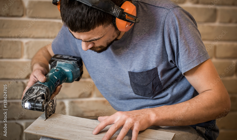 man in headphones works with manual electric saw