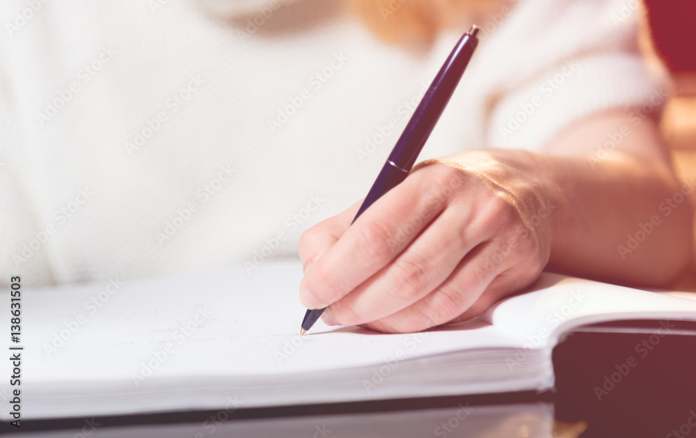 Woman writing in a notebook with a pen Woman writing in a notebook with a pen