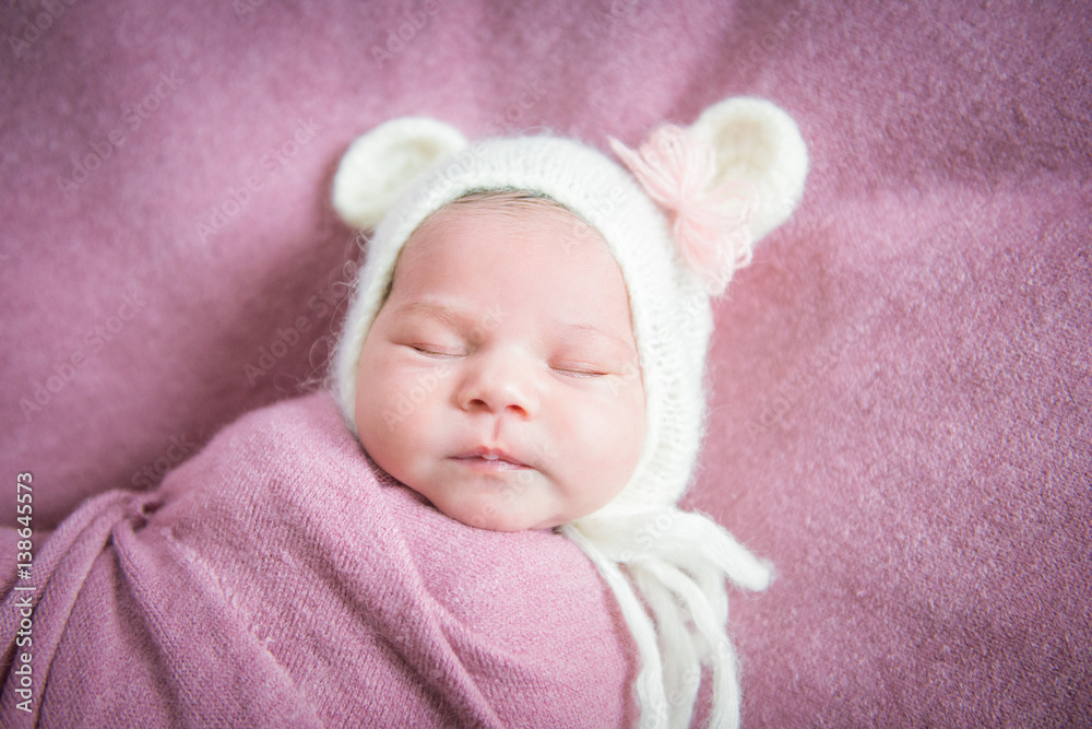 Newborn baby sleeps in a hat with ears on a pink blanket Newborn baby sleeps in a hat with ears on a pink blanket