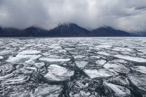 Drifting ice blocks and foggy mountains on background