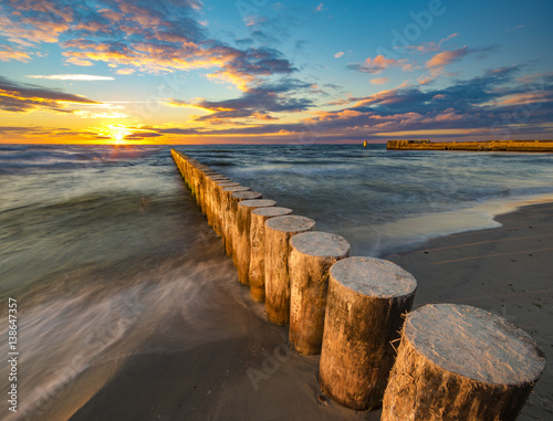 Fototapeta Naklejka Na Ścianę i Meble -  Baltic sea at beautiful sunrise,wooden breakwater in the light of the setting sun