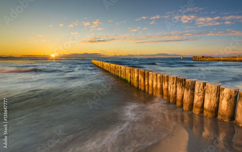 Baltic sea at beautiful sunrise wooden breakwater in the light of the setting sun