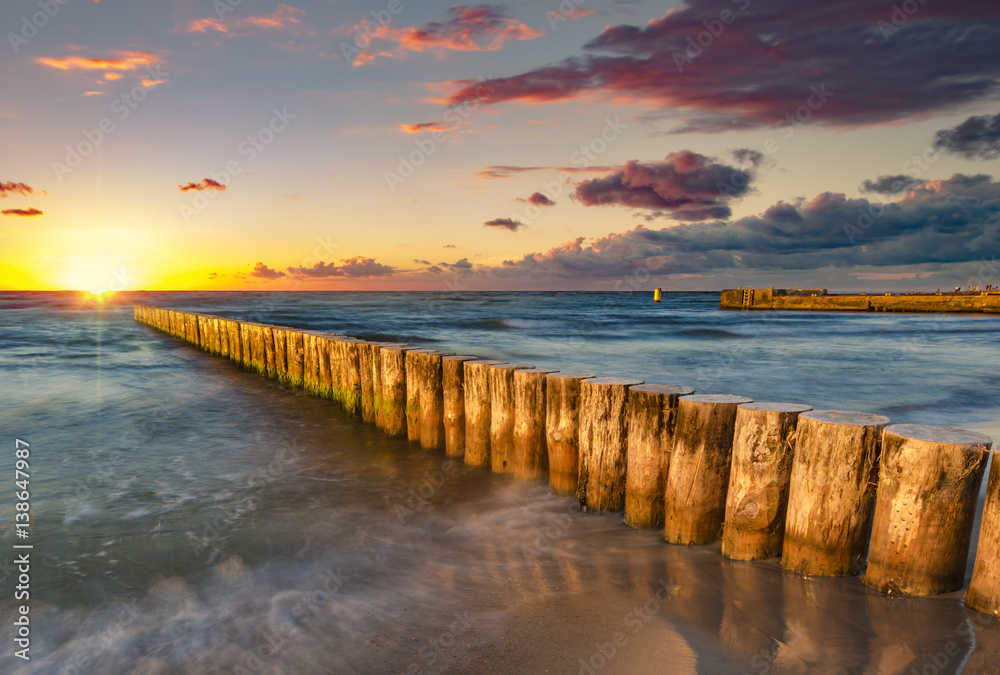 Baltic sea at beautiful sunrise,wooden breakwater in the light of the setting sun