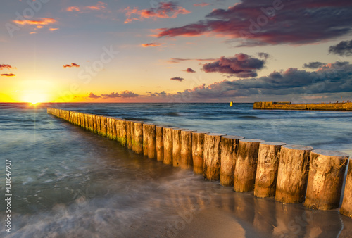Baltic sea at beautiful sunrise wooden breakwater in the light of the setting sun