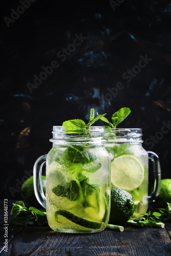 Iced green tea with lime and mint in glass jars, dark background, selective focus