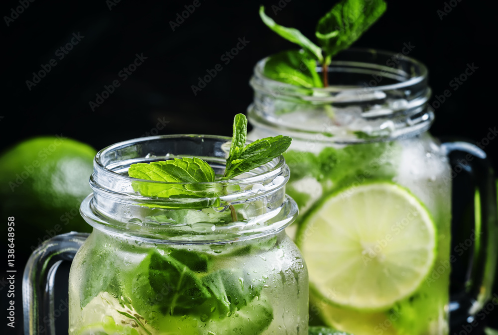 Iced green tea with lime and mint in glass jars, dark background, selective focus Iced green tea with lime and mint in glass jars, dark background, selective focus