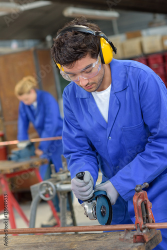apprentice using circular saw in metallurgy workshop