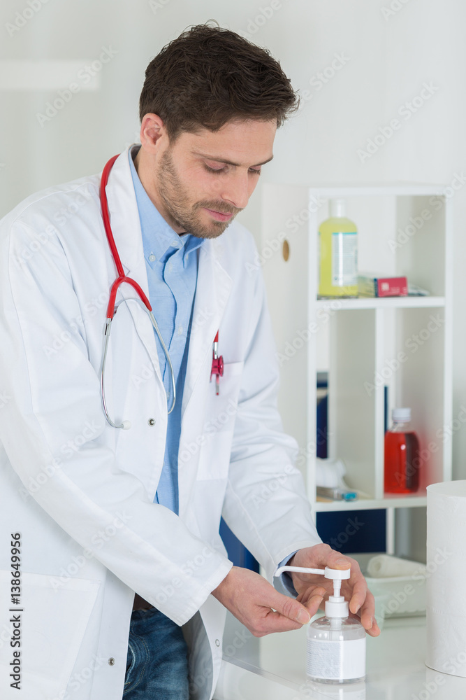 medical doctor using sanitizer dispenser in clinic medical doctor using sanitizer dispenser in clinic
