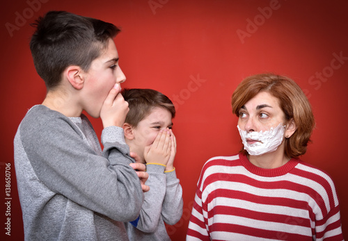 Surprised sons looking at their mother with shaving foam on her face