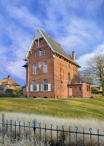 Stately ancient parsonage against cloudy blue sky, Ravels, Flanders, Belgium