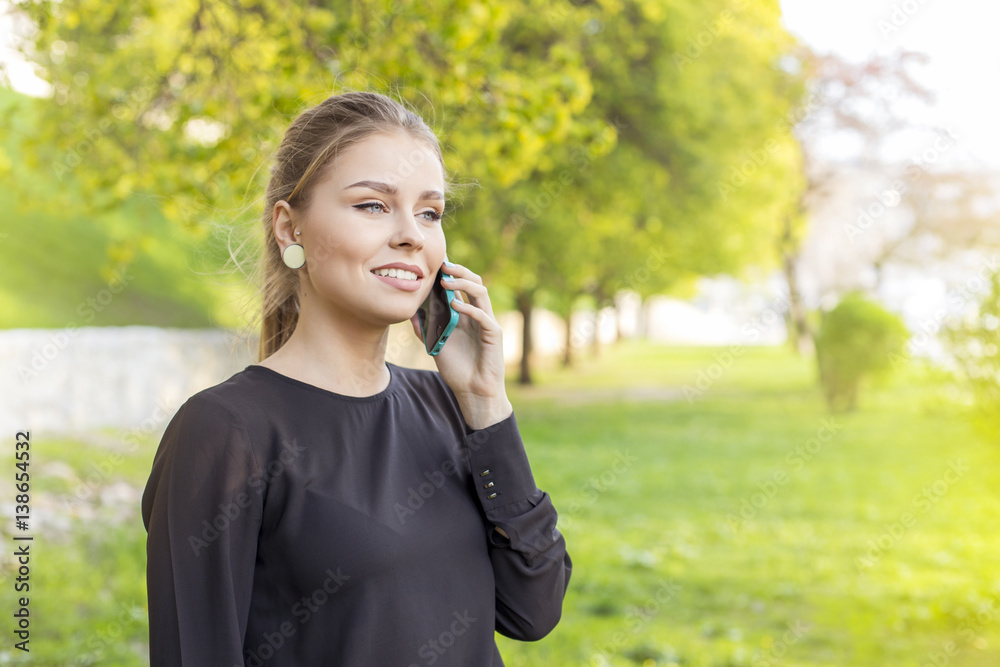 Happy young caucasian business woman talking on the phone, Green leaves blurred background. Spring time Happy young caucasian business woman talking on the phone, Green leaves blurred background. Spring time