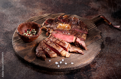 Medium rare grilled beef steak ribeye on a brown rusty background