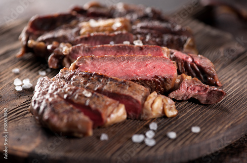 Sliced medium rare grilled beef steak ribeye close-up on a brown rusty background photo