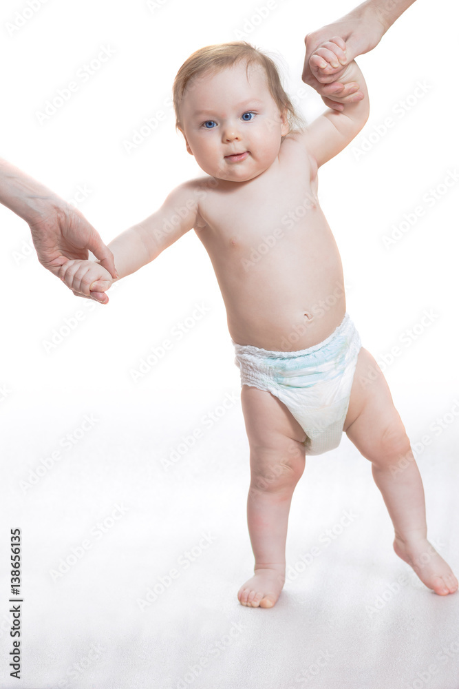 First Steps baby. Little boy is learning to walk with the help of his mother First Steps baby. Little boy is learning to walk with the help of his mother
