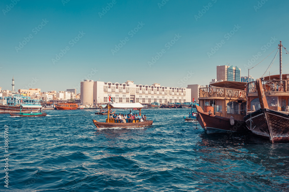 Fototapeta premium Panoramic view from water taxi boats pier in Dubai, UAE. Creek gulf and Deira area. United Arab Emirates famous tourist destination. Creative color post processing.