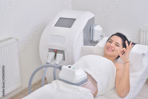 Pretty young woman getting cryolipolyse treatment in professional cosmetic cabinet photo