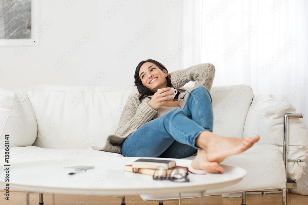 Smiling woman thinking on sofa - obrazy, fototapety, plakaty 