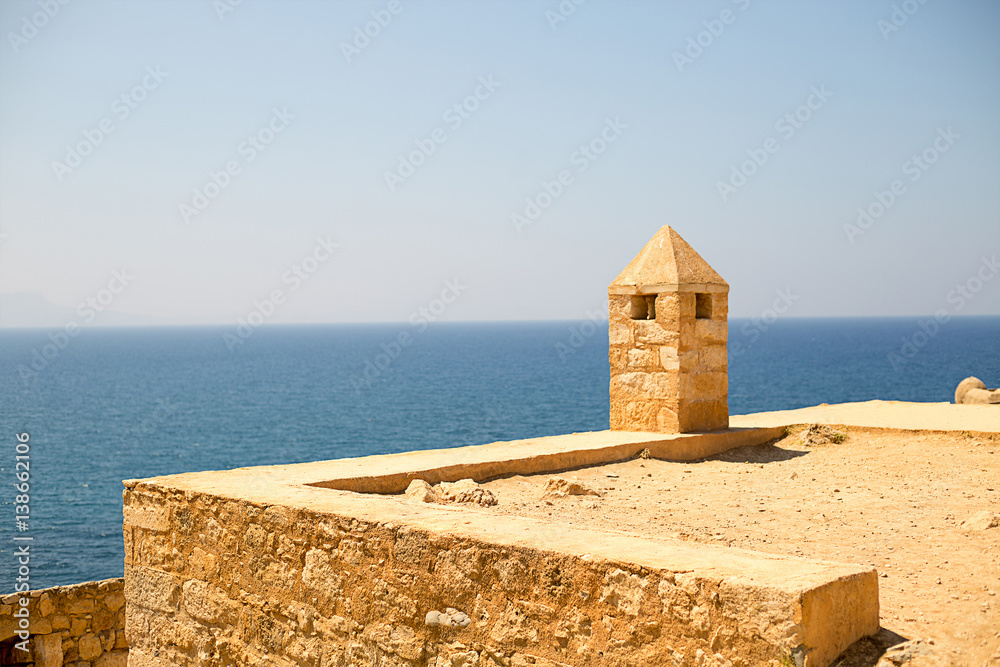 Walk along the old ruins of mediterranean coastal fort castle with a tower from pirimindalnoy roof high above the azure sea