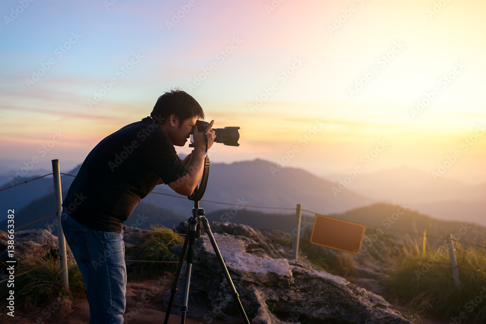 Photographer silhouette above a clouds sea, misty mountains