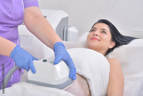 Pretty young woman getting cryolipolyse fat treatment in professional cosmetic cabinet