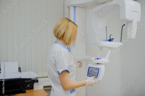 Female dentist sets panoramic teeth x-ray equipment