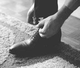 Man tying the laces on black shoes - Black and white photograph in mat tone