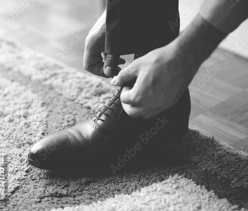 Man tying the laces on black shoes - Black and white photograph in mat tone