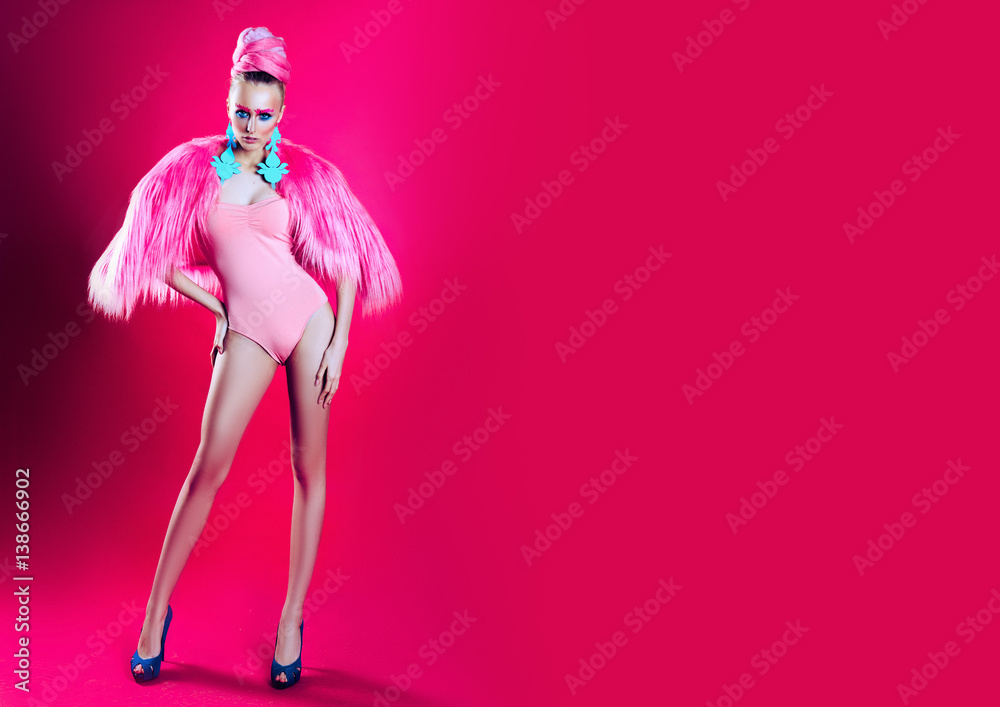 Sexy girl with blue eyes posing in kombidress on a pink background. advertising space