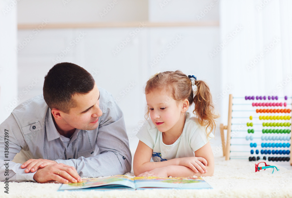 happy father and daughter spending time together by reading interesting book