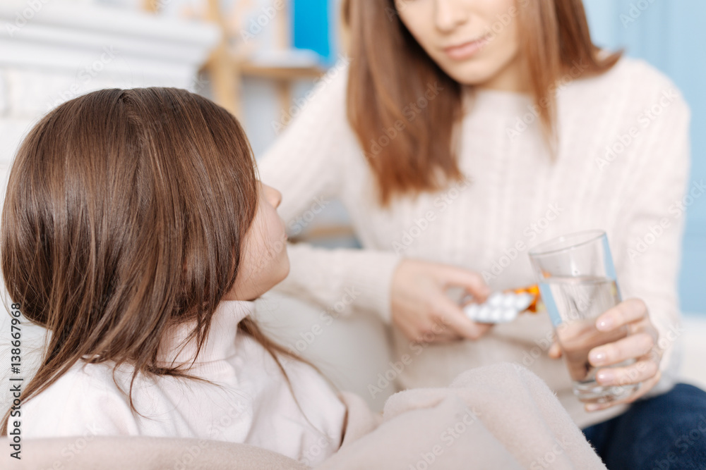 Pleasant sick girl sitting on the couch with her mother Pleasant sick girl sitting on the couch with her mother