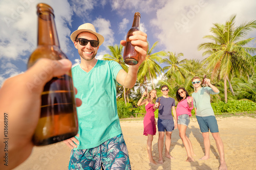 Cheers! Welcome to the beach party. Group of young people drinking beer together on the sea shore. © luengo_ua