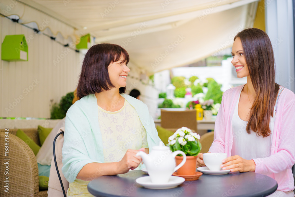 Family day. Aged woman and her adult daughter drinking tea at cafe. Family day. Aged woman and her adult daughter drinking tea at cafe.