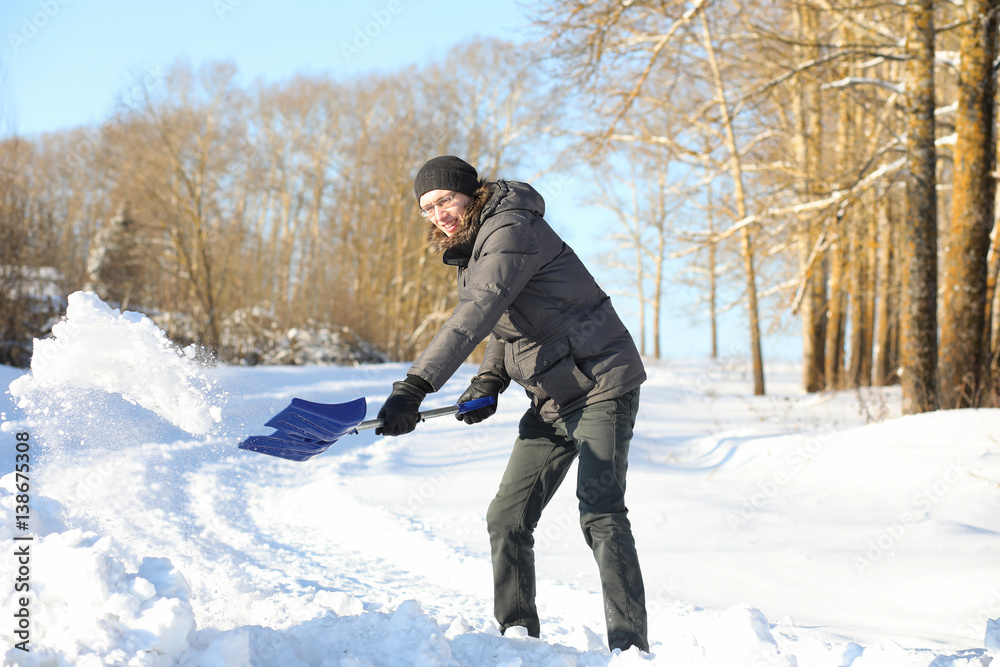 man remove snow with shovel from the road in winter