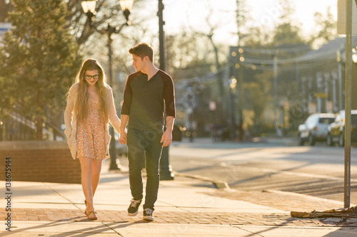 Fotografie Young couple walking down the sidewalk holding hands