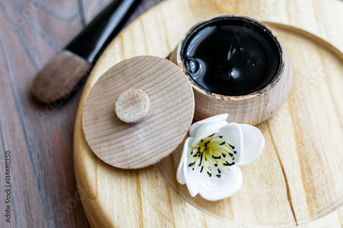 black substance in wooden jar on a wooden background. Black Mask 