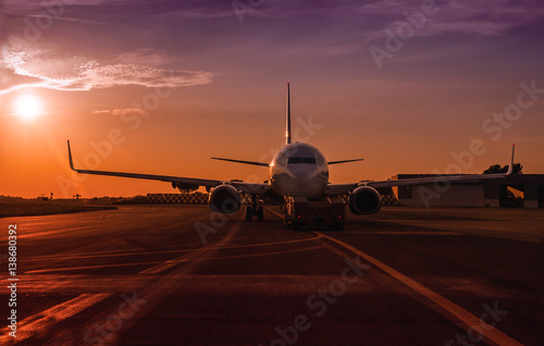 Commercial passenger jet in an airport at the sunset.
