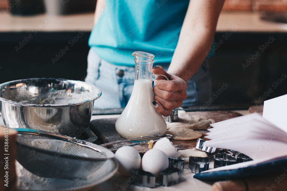 Woman holding bottle with milk while baking