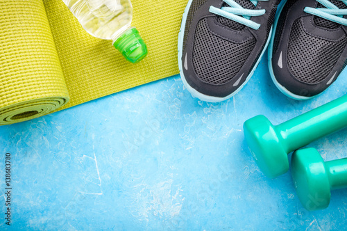 Yoga mat, sport shoes, dumbbells and bottle of water on blue background. Concept healthy lifestyle, sport and diet. Sport equipment. Copy space © missmimimina